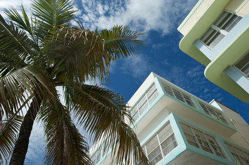 Fototapeta na wymiar Sunny architectural detail view of Art Deco buildings in South Beach with a palm tree under blue sky in Miami, Florida, USA