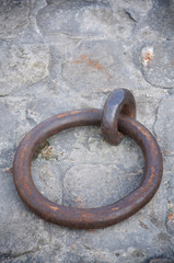 Massive rusted iron ring sitting on rough textured stone background on the wall of the quay in Paris, France