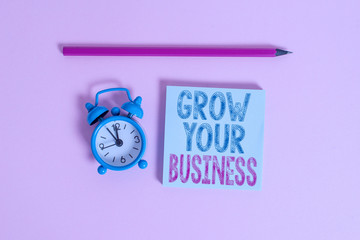 Word writing text Grow Your Business. Business photo showcasing Achieve higher profit Provide better return of investment Metal vintage alarm clock wakeup blank notepad marker colored background
