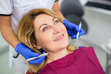dentist examining mature woman's teeth in clinic
