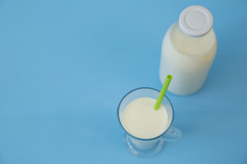 bottle of organic milk and glass of milk on the blue background with copy space for text. Dairy products background.