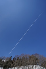 Fototapeta na wymiar 冬山の青空にスラッシュのような飛行機雲