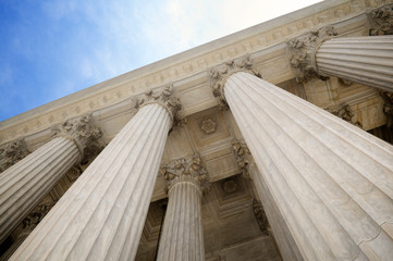 Low angle view of grand classical stone columns soaring up to decorative entablature at the Supreme Court building in Washington DC, USA