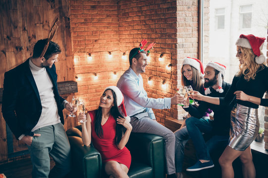 Photo of six members group x-mas party couples people friendship buddies clinking wineglasses drink golden wine wear formalwear santa hats deer horns indoors
