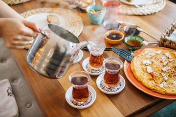 Pouring tea from tea pot to glass. Breakfast preparation concept. Traditional Turkish brewed tea drink in morning also as known 