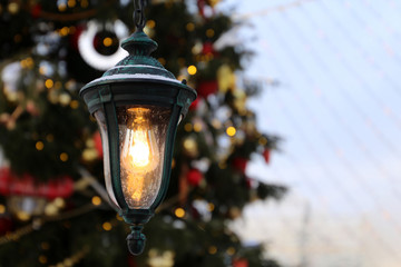 Christmas tree with decorations and vintage flickering lantern on a city street during snow. New...
