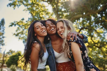 Fotobehang Portrait of a happy multiethnic group of smiling female friends - women laughing and having fun in the park on a sunny day © StratfordProductions