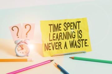 Text sign showing Time Spent Learning Is Never A Waste. Business photo text education has no end Keep learning Mini size alarm clock beside stationary placed tilted on pastel backdrop