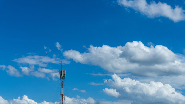 Telecommunication telephone signal transmission tower with cloud and blue sky background.