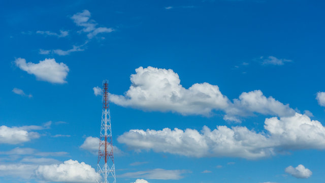 Telecommunication telephone signal transmission tower with cloud and blue sky background.