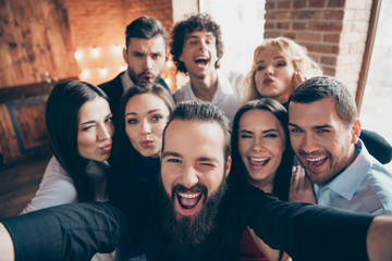 Photo of cheerful nice cool company of people fooling in front of camera near friend taking selfie kissing winking in formalwear