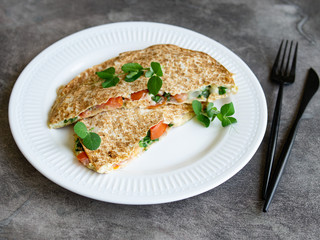 Vegetarian healthy breakfast of melted thin pita bread, cheese, tomato and herbs on a white plate and gray background. Diet. Selective focus, close up, copy space