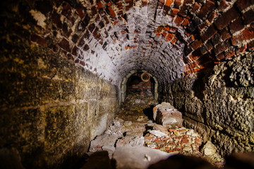 Old collapsed red brick underground vaulted historical sewer tunnel, selective focus