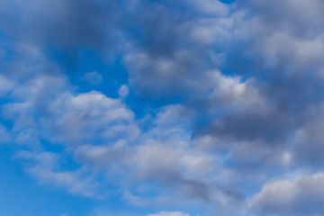 Beautiful white clouds on a background of blue sky. Defocused image for design.
