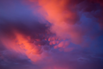 Unusual pink-purple mammatus clouds at sunset. Blurred image for backgrounds.