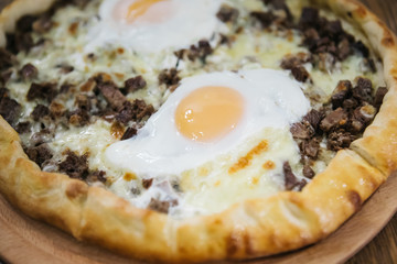 Turkish traditional round pita bread (Turkish pide) with cheese, eggs and meat