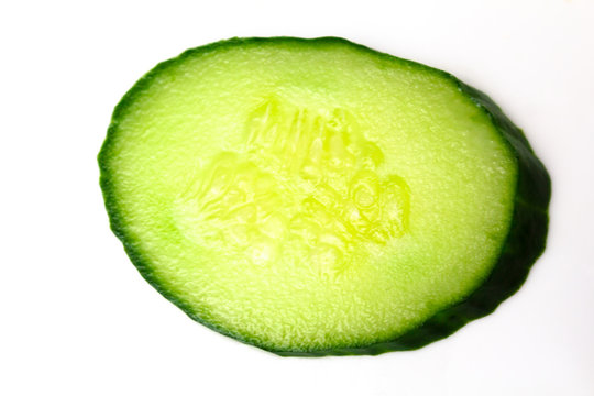 Ripe green cucumber on slices on a white background