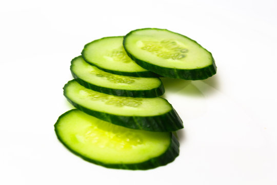 Ripe green cucumber on slices on a white background