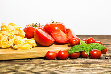 TOMATOES ON A BOARD WITH BASIL AND SPICES