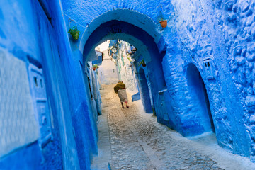 A traditional dressed moroccan woman walks in the old town (medina) of Chefchaouen in Morocco.