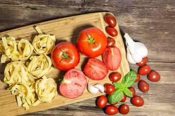 TOMATOES ON A BOARD WITH BASIL AND SPICES