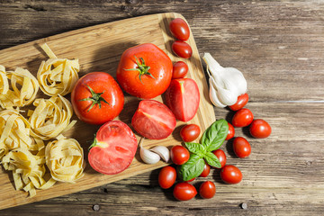 TOMATOES ON A BOARD WITH BASIL AND SPICES