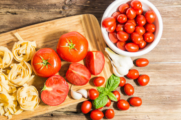 TOMATOES ON A BOARD WITH BASIL AND SPICES