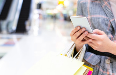 Cashback concept. Woman with smartphone in mall