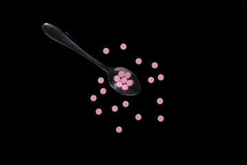 flat lay of pile on spoon isolated black background, the concept of save our heart and liver with minimize pile consumption