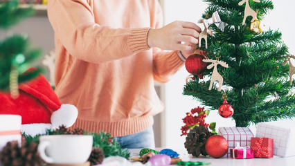 Woman hands decorating the christmas tree and christmas wreath.