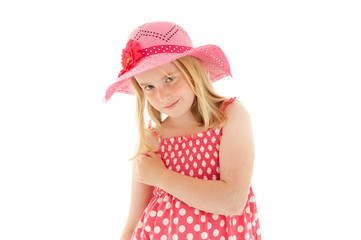 Beautiful young blonde girl with enigmatic smile wearing big pink floppy hat and a polka dot dress....