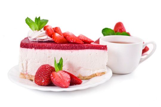 Piece of cheesecake with fresh strawberries, mint and cup of tea isolated on a white background