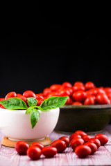 CHERY TOMATOES ON BLACK BACKGROUND WITH BASIL AND JUICE WITH SELECTIVE FOCUS