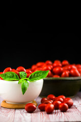 CHERY TOMATOES ON BLACK BACKGROUND WITH BASIL AND JUICE WITH SELECTIVE FOCUS