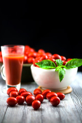 CHERY TOMATOES ON BLACK BACKGROUND WITH BASIL AND JUICE WITH SELECTIVE FOCUS