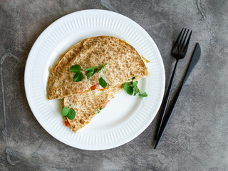 Vegetarian healthy breakfast of melted thin pita bread, cheese, tomato and herbs on a white plate and gray background. Diet. Selective focus, close up, copy space