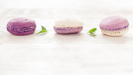 French confectionery. Violet macaroons. White wooden background.