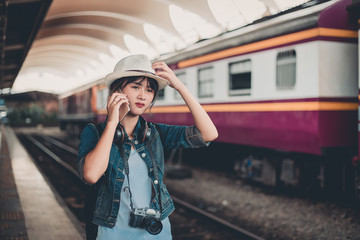 Commuter traveler woman waiting train in railway station - Cute girl caucasian guy standing on platform using mobile with locomotive background - Soft desaturated vintage filter