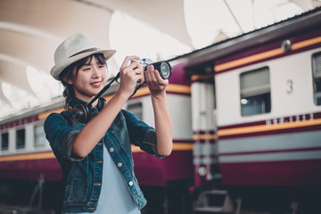 Commuter traveler woman looking down at camera waiting train in railway station - Cute girl caucasian guy standing on platform using cam with locomotive background - Soft desaturated vintage filter