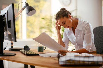 Beautiful businesswoman in office. Tired woman having headache while working.