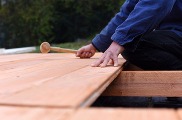 Handy carpenter installing wooden planks during flooring works outside the new house. Czech...