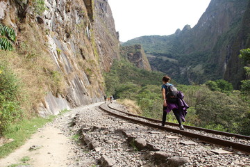 Aguas Calientes, Peru »; August 2017: A young woman walking along the train tracks in Trekking to get to Aguas Calientes