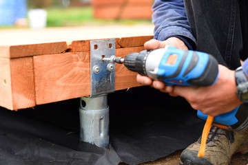 Handy carpenter installing wooden planks during flooring works outside the new house. Czech...