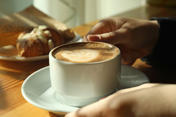 Woman with cup of fresh aromatic coffee at table in cafe