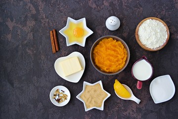 Ingredients for making American pumpkin pie: pumpkin puree, flour, butter, spices, salt, cream, brown and white sugar, egg, lemon. Thanksgiving dessert recipe. Top view.