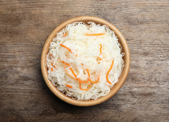 Tasty fermented cabbage on wooden table, top view