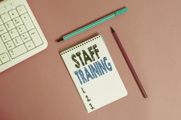 Conceptual hand writing showing Staff Training. Concept meaning program that helps employees learn specific knowledge Writing equipments and computer stuff placed on plain table
