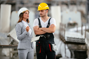 Architect and worker working on project. Colleagues discussing work in factory.