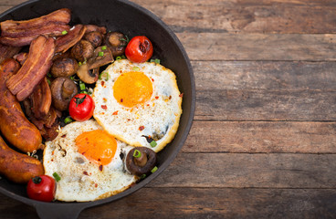 Fried eggs, bacon and sausages in the pan 