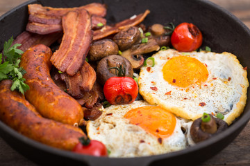 Fried eggs, bacon and sausages in the pan 